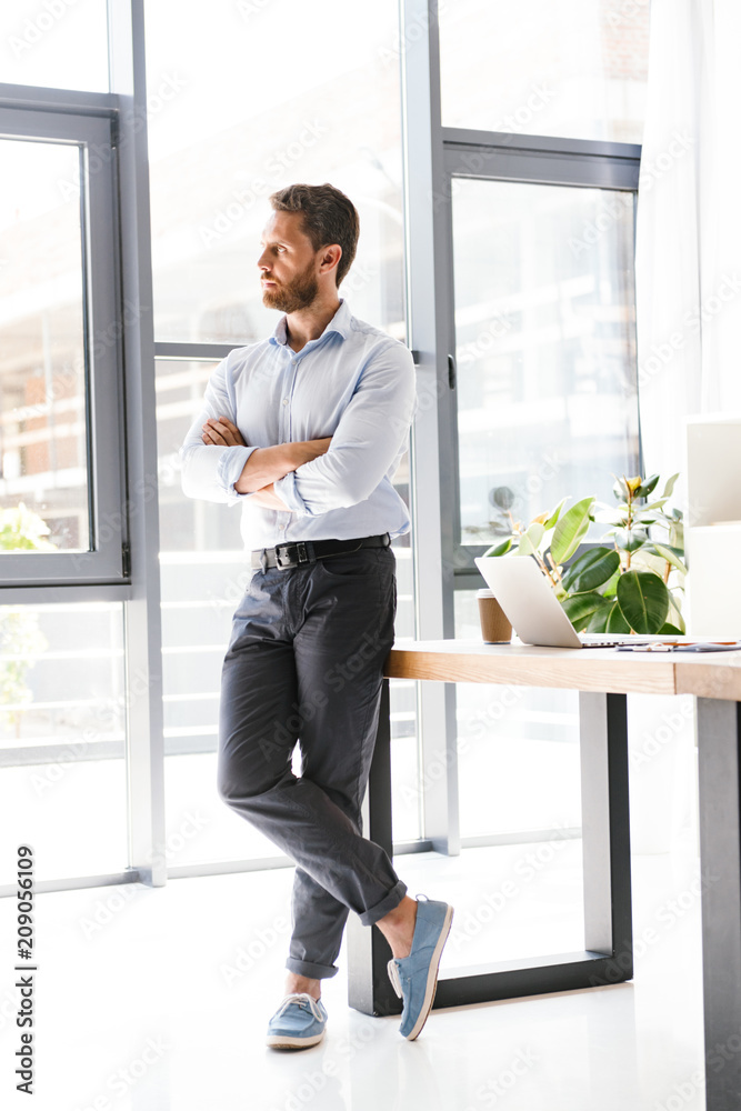 Fototapeta premium Handsome bearded man in office standing near table