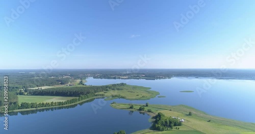 High smooth aerial shot of two lakes meeting via tongues of green fields and forests