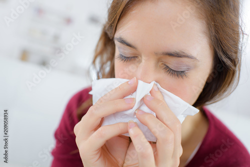 burnette woman blowing nose into tissue photo