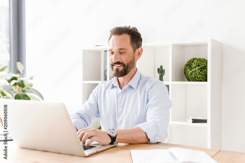 Smiling businessman working on laptop computer Smiling businessman working on laptop computer
