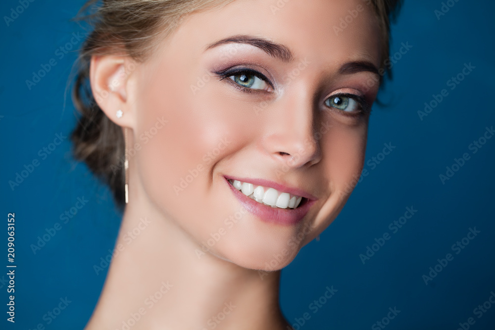 Young smiling woman face on blue background, closeup portrait. Cute smile Young smiling woman face on blue background, closeup portrait. Cute smile