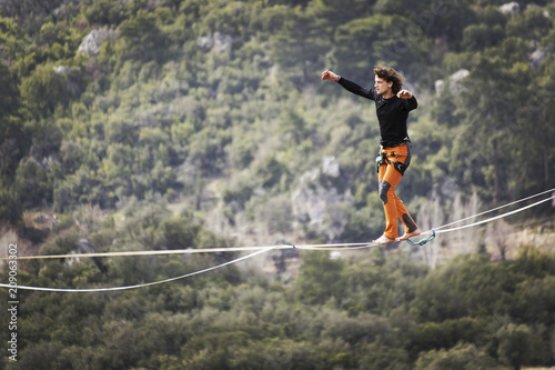 Highliner on a rope. Highline on a background of mountains. Extreme sport on the nature. Balancing on the sling. Equilibrium at altitude.