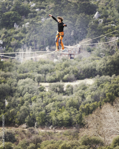 Highliner on a rope. Highline on a background of mountains. Extreme sport on the nature. Balancing on the sling. Equilibrium at altitude.