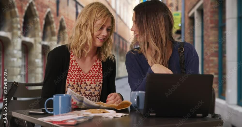 Lovely blonde woman with girlfriend using smartphone to locate destination in Bruges, Belgium, Two cute young adult women looking at cell phone with map in European street cafe, 4k Lovely blonde woman with girlfriend using smartphone to locate destination in Bruges, Belgium, Two cute young adult women looking at cell phone with map in European street cafe, 4k