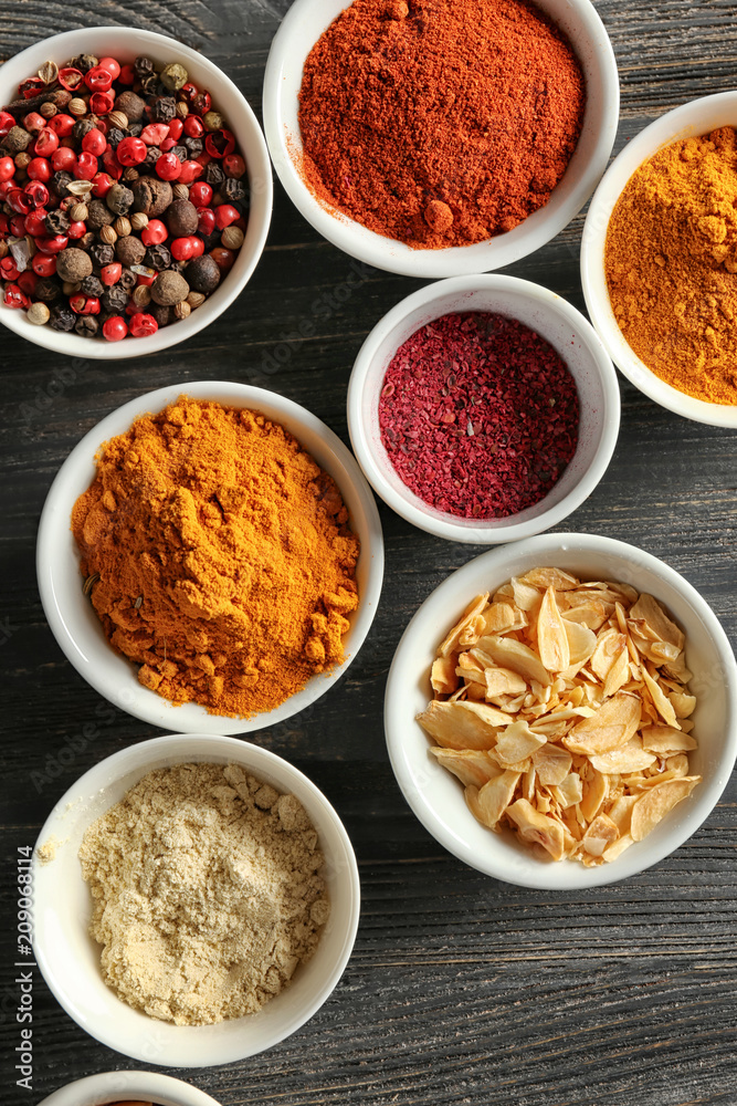 Bowls with various spices on wooden background