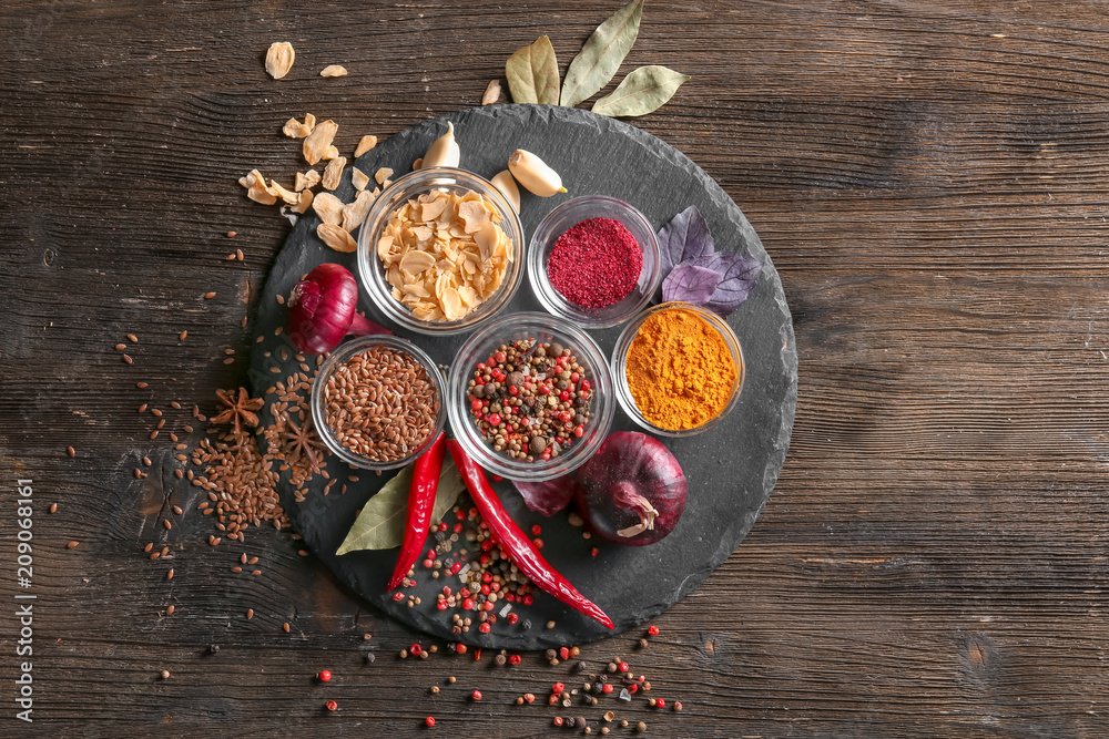 Slate plate with various spices on wooden background Slate plate with various spices on wooden background