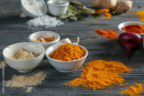 Bowls with various spices on wooden background