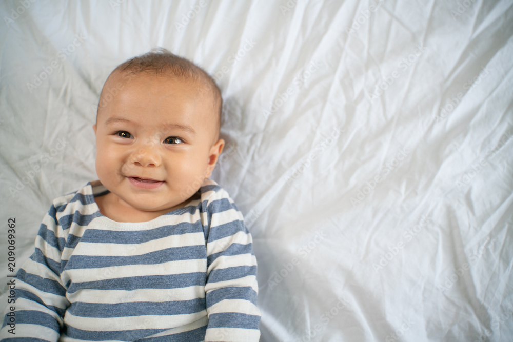 The little boy smiles in the bed in his own room The little boy smiles in the bed in his own room