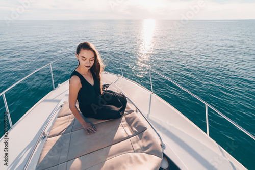 a stylish young girl in black summer clothes sits in her boat, sails the Caribbean sea to the islands © nelen.ru