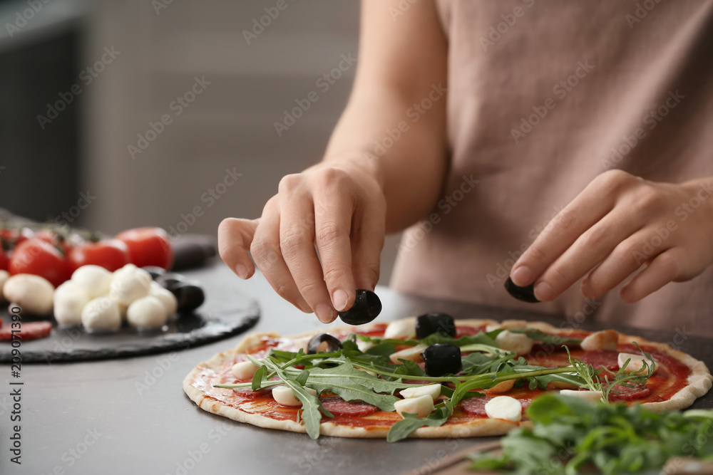 Woman preparing pizza at table in kitchen Woman preparing pizza at table in kitchen
