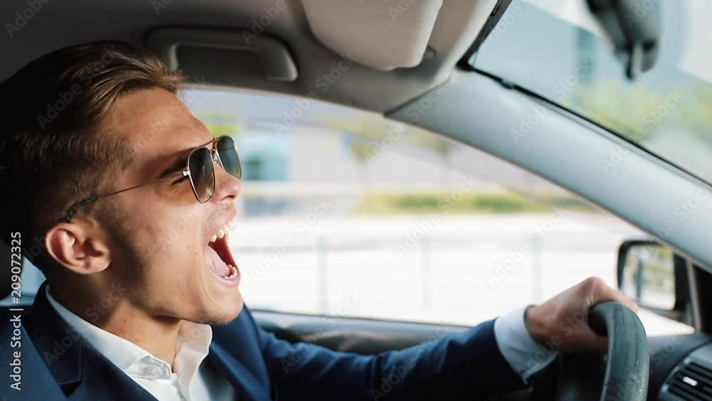 Depressed and very upset young businessman in the car. A man drinks alcohol at the wheel problems in business or personal life