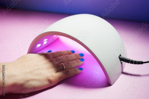 UV lamp gel polish for manicure. A female hand is dried gel nail polish.