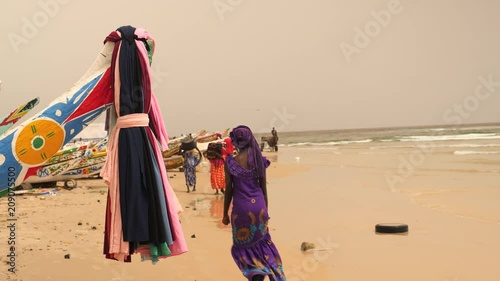 Africa: fishermen's beach with colorful fishing boats and women in traditional dress in Senegal. photo