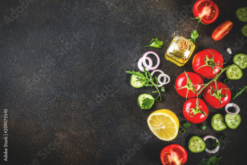 Cooking background, fresh salad ingredients, italian cuisine - tomatoes, olive oil, lemon, cucumbers, arugula, parsley, onions, Dark rusty background copy space top view