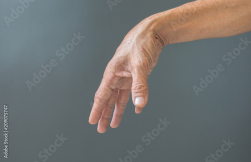 The gesture of rough hands and wrinkles of the elderly on a gray