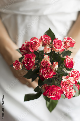 Woman holding bouquet of pink small roses