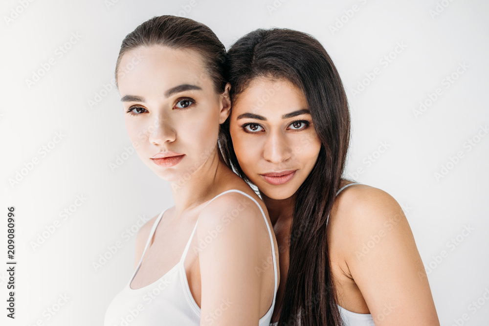 portrait of attractive multicultural women looking at camera isolated on gray background