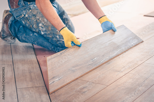 Professional installation of floor covering, the worker quickly and qualitatively mounts a laminate board