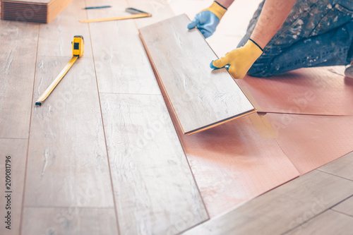 Worker professionally installs floor boards