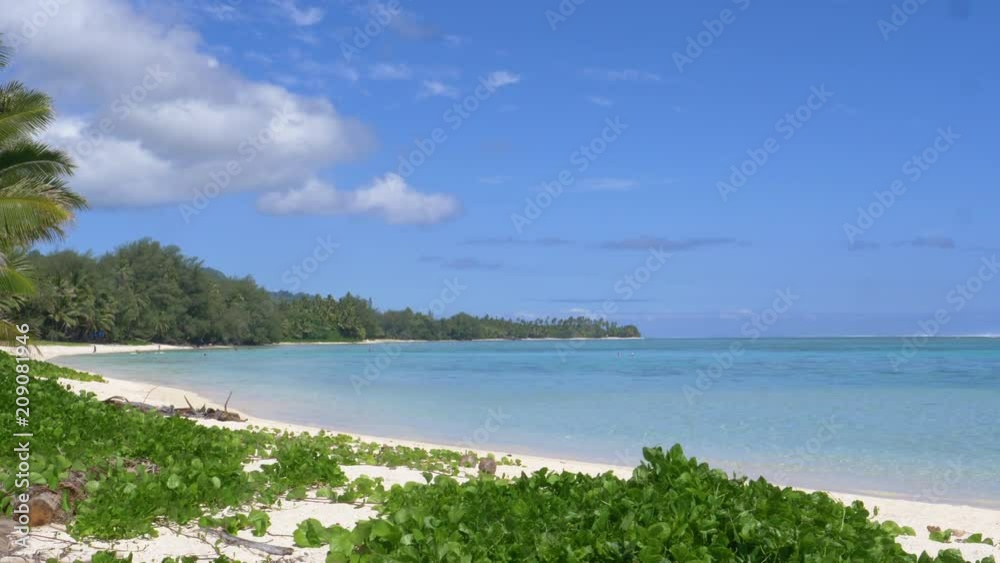 Breathtaking paradise island coast is being explored by unrecognizable tourists and man snorkeling in the crystal clear ocean. Picturesque view of lush exotic greenery covering the white sand beach. Breathtaking paradise island coast is being explored by unrecognizable tourists and man snorkeling in the crystal clear ocean. Picturesque view of lush exotic greenery covering the white sand beach.