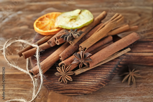 Board with aromatic cinnamon sticks on wooden background