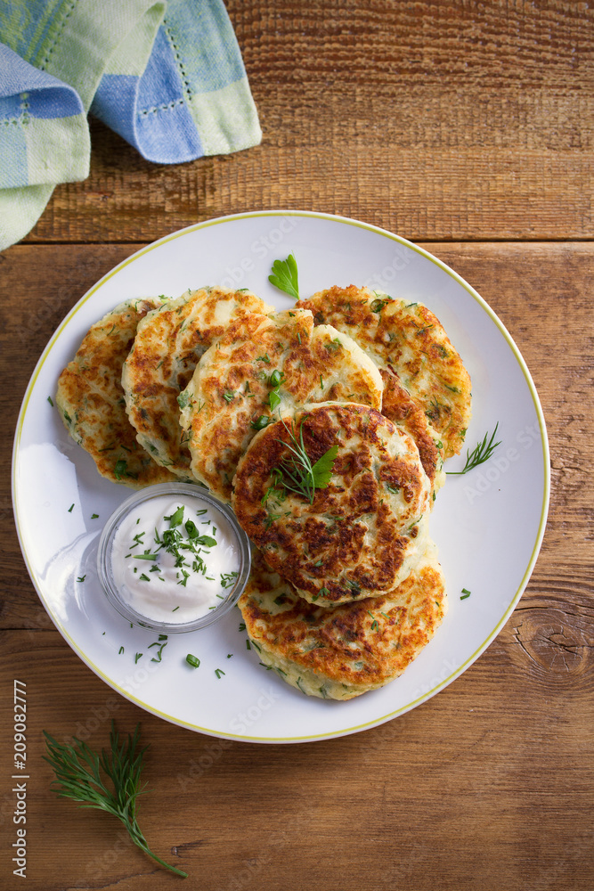 Mashed potato and cheese cakes, served with sour cream or yogurt. Potato Pancakes, Fritters. overhead, vertical Mashed potato and cheese cakes, served with sour cream or yogurt. Potato Pancakes, Fritters. overhead, vertical