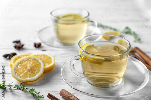 Cup of hot aromatic beverage with lemon on table