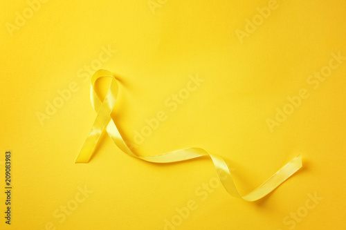 Yellow ribbon on color background. Cancer concept