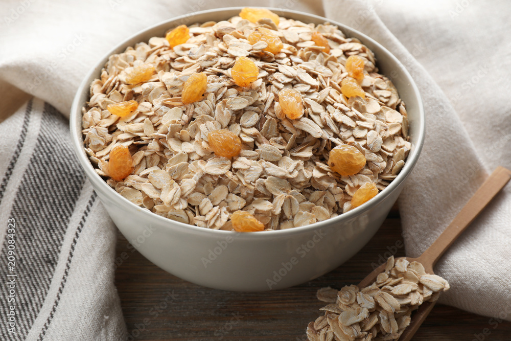 Bowl with oat flakes and raisins on wooden table Bowl with oat flakes and raisins on wooden table
