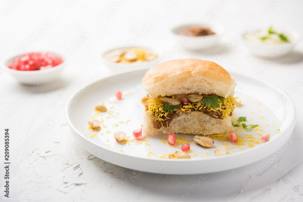 Dabeli is an Indian snack item served with Pomegranate Seeds and Cilantro in white ceramic plate. It's a popular Navratri Festival food Dabeli is an Indian snack item served with Pomegranate Seeds and Cilantro in white ceramic plate. It's a popular Navratri Festival food