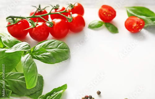 Fresh basil and tomatoes on light background