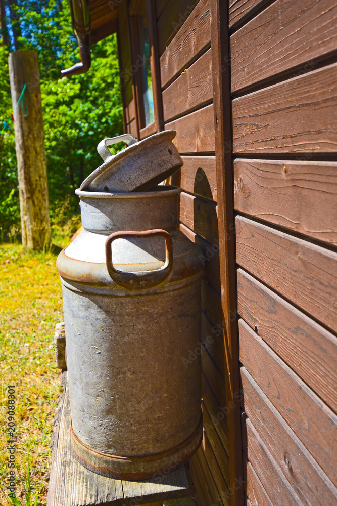 Old milk jug on the wooden wall of a shed in bright sunlight Old milk jug on the wooden wall of a shed in bright sunlight