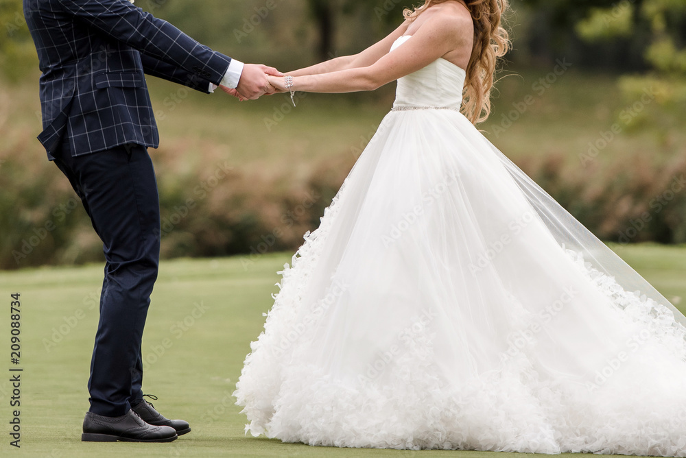 Portrait of lovely wedding couple dancing on green lawn of golf course, copy space. Happy bride and groom holding hands outdoors, free space Portrait of lovely wedding couple dancing on green lawn of golf course, copy space. Happy bride and groom holding hands outdoors, free space