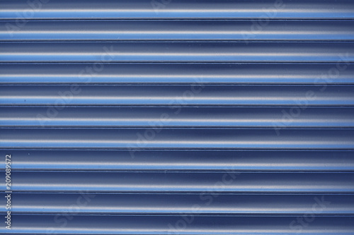 Surface textured horizontal, striped, blue facing wall, siding.