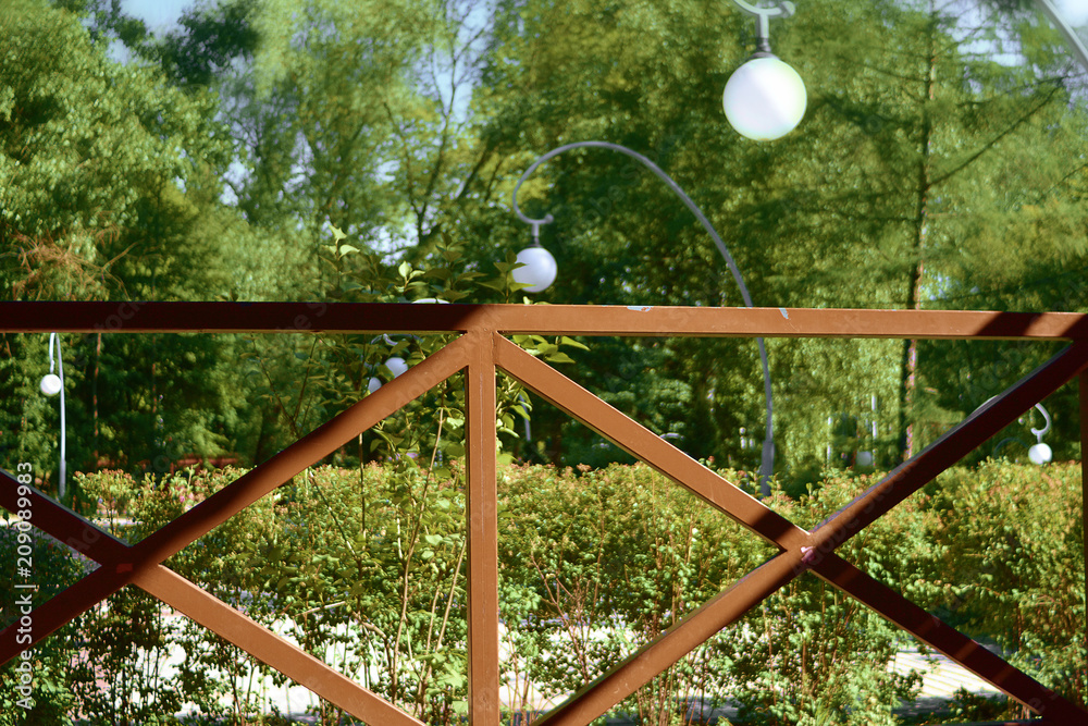 Wooden painted cross-shaped fence in the park with a lantern on a sunny day.