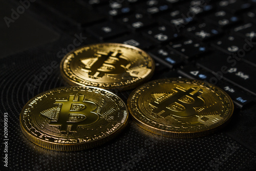 Three coins of bitcoin on a black laptop on a table