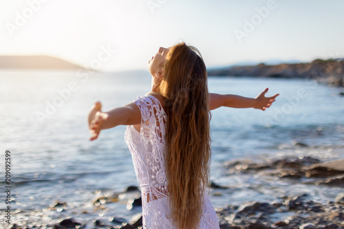 Junge Frau streckt ihre Arme am Strand aus und genießt die Freiheit und Ruhe photo