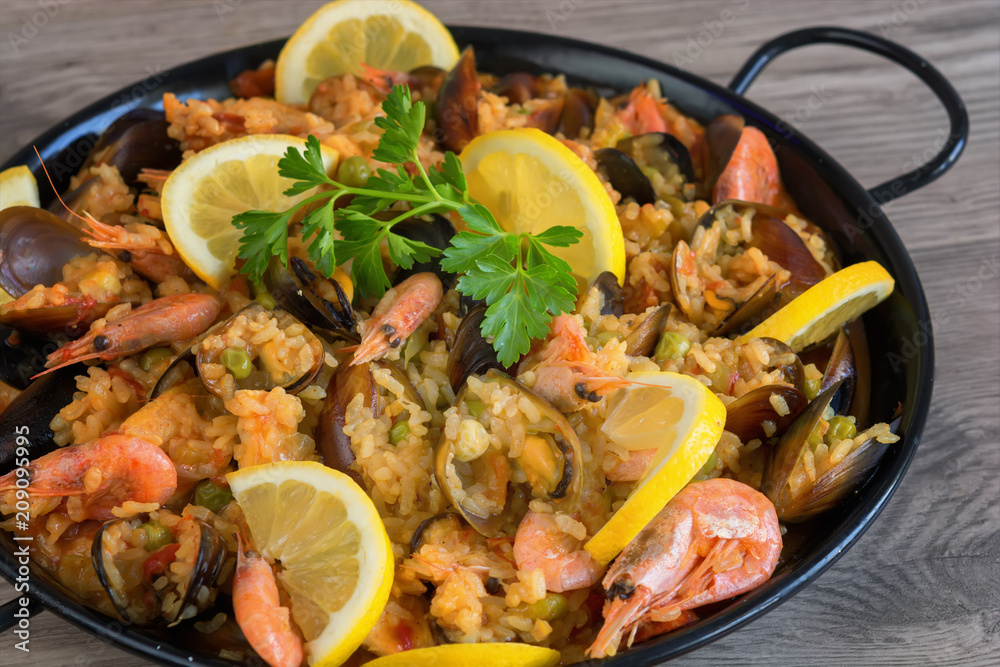 Traditional spanish seafood paella in pan rice, peas, shrimps, mussels, squid on light grey concrete background Traditional spanish seafood paella in pan rice, peas, shrimps, mussels, squid on light grey concrete background