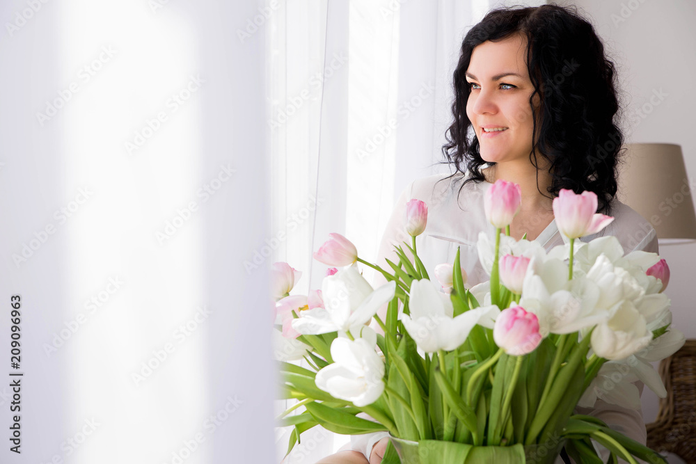 young woman sits on a window with a bouquet of flowers
