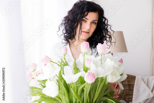 young woman sits on a window with a bouquet of flowers