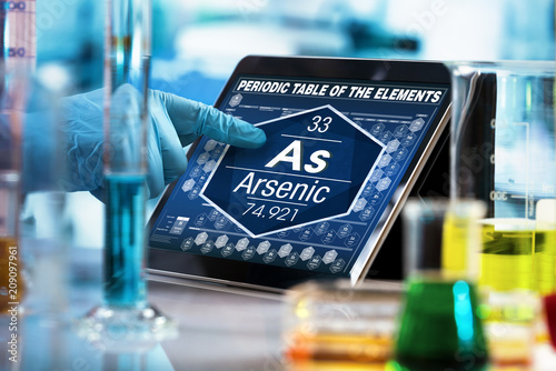 researcher consulting on the digital tablet data of the chemical element Arsenic As / scientist working on the computer with the periodic table of elements