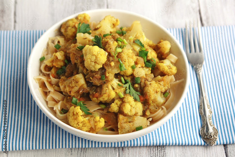 Cauliflower stew with curry. European cuisine. Ribbon pasta topped with vegetables. Vegan lunch. Simple homemade dishes. Vegetables and pasta. Main course.