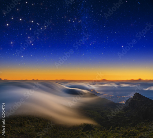 A magnificent spectacle of flowing clouds over the mountains at sunrise over Tenerife at night
