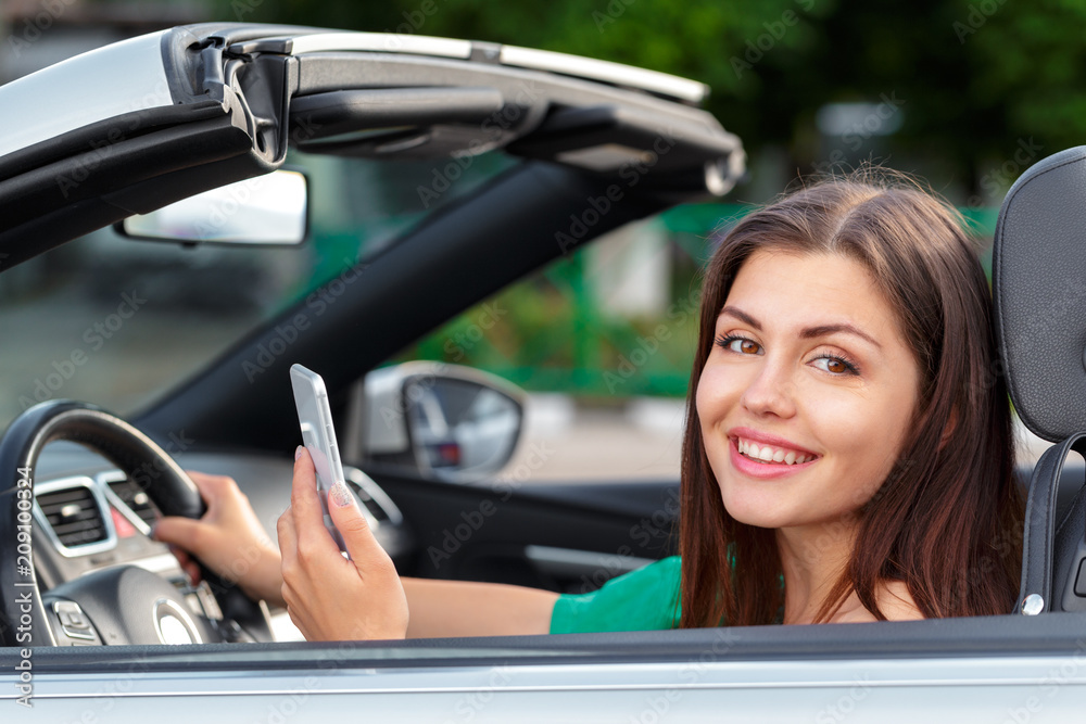 Business woman sitting in car and using her smartphone.