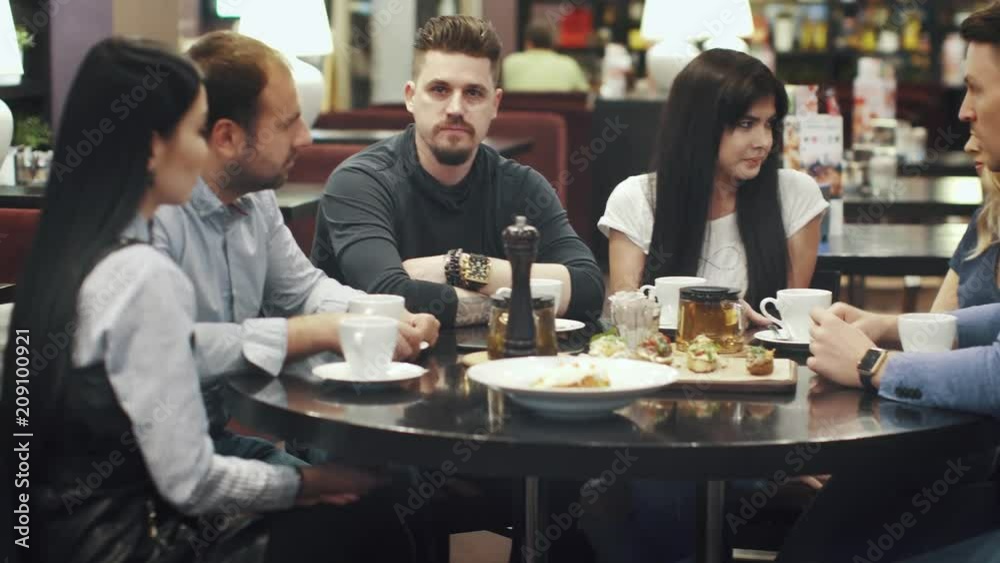 large group of friends talking and having fun together sitting at a table in a cafe or restaurant large group of friends talking and having fun together sitting at a table in a cafe or restaurant