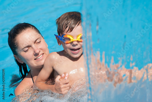 mother and child in goggles playing in swimming pool in summer sunny day