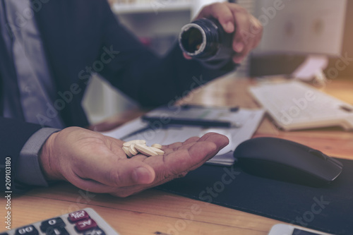 Cuadro en lienzo Stressed businessman having severe headache, holding painkiller remedy pill