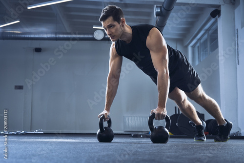 Man doing pushups on kettlebells at gym