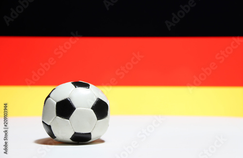 Small football on the white floor with black red and yellow color of German nation flag background. The concept of sport.