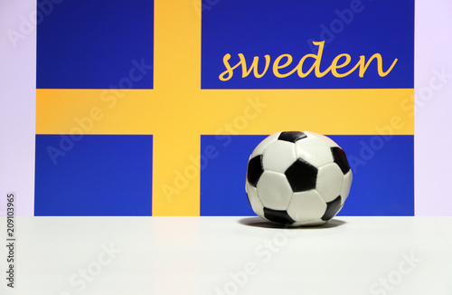 Small football on the white floor and Swedish nation flag with the text of Sweden background. The concept of sport. photo